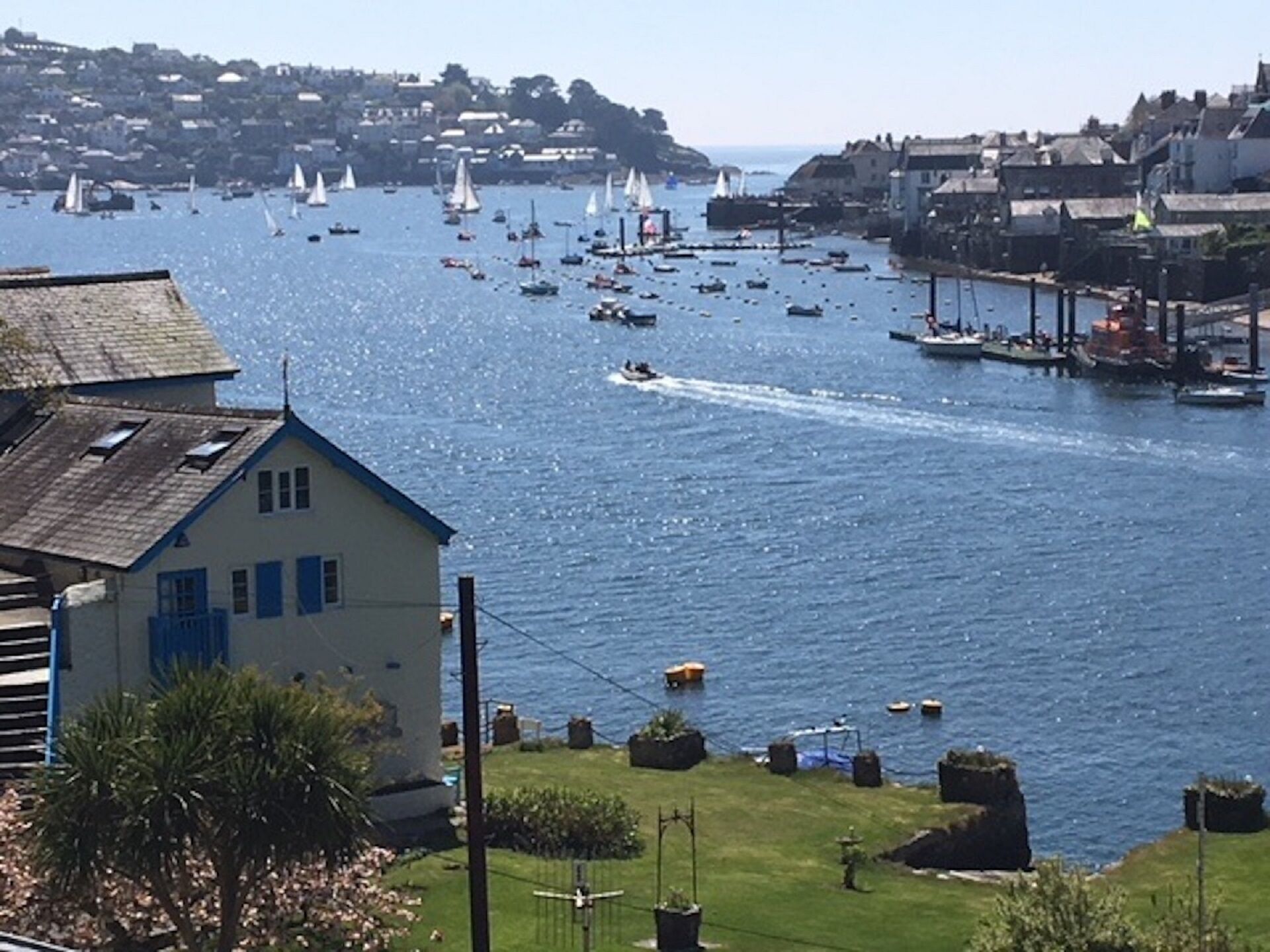 A coastal town with a marina filled with boats, a lighthouse, and residential buildings.