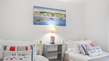 Cozy retreat with two single beds, a bedside table, and a wall-mounted shelf, perfect for a comfortable stay.