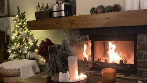 Una sala acogedora con chimenea, un árbol de Navidad y una mesa de centro de madera con velas.