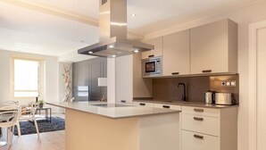 A modern kitchen with a central island, built-in microwave, and stainless steel appliances.