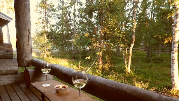 A wooden deck with a bench and three wine glasses, overlooking a forested area. - Traditional Ski Cabin in lovely forest setting in Äkäslompolo, Ylläs (Kolari)