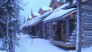A row of log cabins with snow-covered roofs and a wooden deck in front. - Traditional Ski Cabin in lovely forest setting in Äkäslompolo, Ylläs (Kolari)