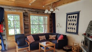 A cozy log cabin interior with a sofa, chairs, a coffee table, and a fireplace. - Traditional Ski Cabin in lovely forest setting in Äkäslompolo, Ylläs (Kolari)