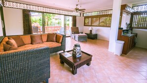 A spacious living area with a sofa, chairs, a coffee table, and a ceiling fan.