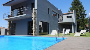 Ein modernes, zweistöckiges Haus mit Schwimmbad, Außenbereich und einer Steinsäule.