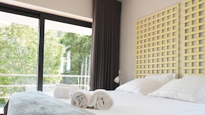 Ein Hotelzimmer mit einem großen Bett, Blick auf Bäume durch ein Fenster und einem hölzernen Kopfteil.