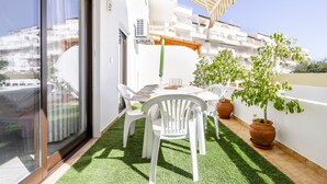 A balcony with a table, chairs, potted plants, and a view of the cityscape.