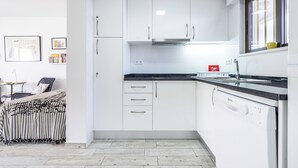 A modern kitchen with white cabinets, a dishwasher, and a window with a view.
