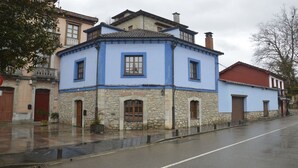 Ein zweistöckiges Gebäude mit rustikalem Steinfundament und blauen Obergeschossen, ausgestattet mit zahlreichen Fenstern und einem roten Dach.