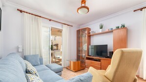 Een woonkamer met een bank, fauteuil en tv-meubel.