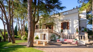 A villa with a stone staircase leading to a balcony, surrounded by lush greenery and a well-maintained lawn. - An exclusive historic villa with private pool (Fasano)