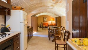 A kitchen with a white refrigerator, wooden cabinets, a dining table with chairs, and a tiled floor. - An exclusive historic villa with private pool (Fasano)