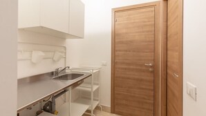 Una cocina compacta con un lavamanos de acero inoxidable, armarios blancos y una puerta de madera.