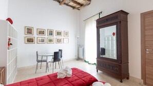 Una habitación con dos camas, un armario de madera, una mesa de comedor con sillas y un radiador.