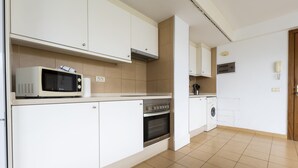A modern kitchen with white cabinets, a microwave, an oven, and a washing machine. - Sea Terrace (Socorro, El (Guimar))