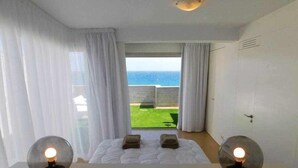 A bedroom with a bed, two bedside lamps, a view of the sea, and a balcony. - Sea Terrace (Socorro, El (Guimar))