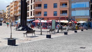 A public square with outdoor seating, a sculpture, and buildings in the background. - Sea Terrace (Socorro, El (Guimar))