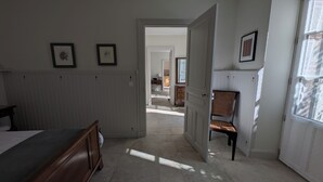 A bedroom with a bed, a chair, and a door leading to another room. - Delightful Gite in SW France - Private Garden, Close to Town & beautiful walks   (Mazamet)
