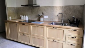 A kitchen with a stainless steel sink, wooden cabinets, a range hood, and a countertop with a cutting board and utensils. - Delightful Gite in SW France - Private Garden, Close to Town & beautiful walks   (Mazamet)