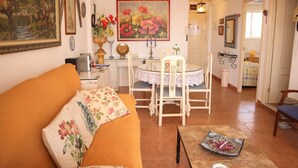 A cozy living room with a sofa, a dining table with chairs, and a painting on the wall. - Coronado 129 Apartment by Casasol (Nerja)
