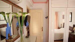 A hotel room with a bed, a dresser, a mirror, and a vase with flowers. - Coronado 129 Apartment by Casasol (Nerja)