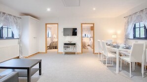 Una habitación amplia con comedor, televisor y cama.