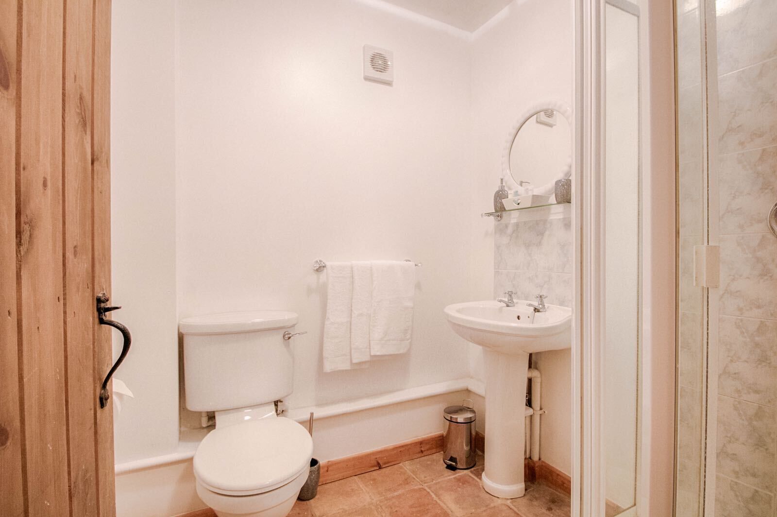 A small, clean bathroom with a toilet, sink, and shower.