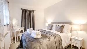 Un dormitorio con cama, mesitas de noche, tocador y espejo.