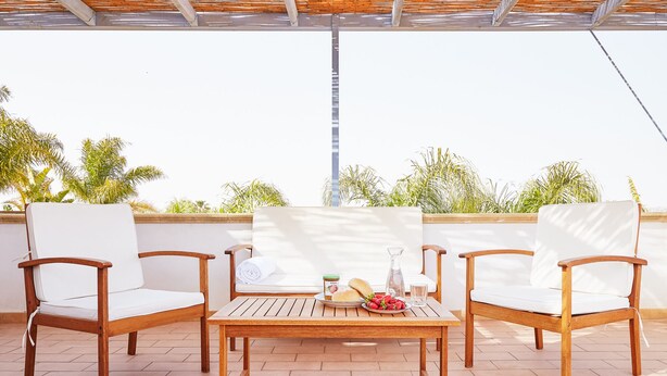 Een terras met houten meubels, een tafel en stoelen.