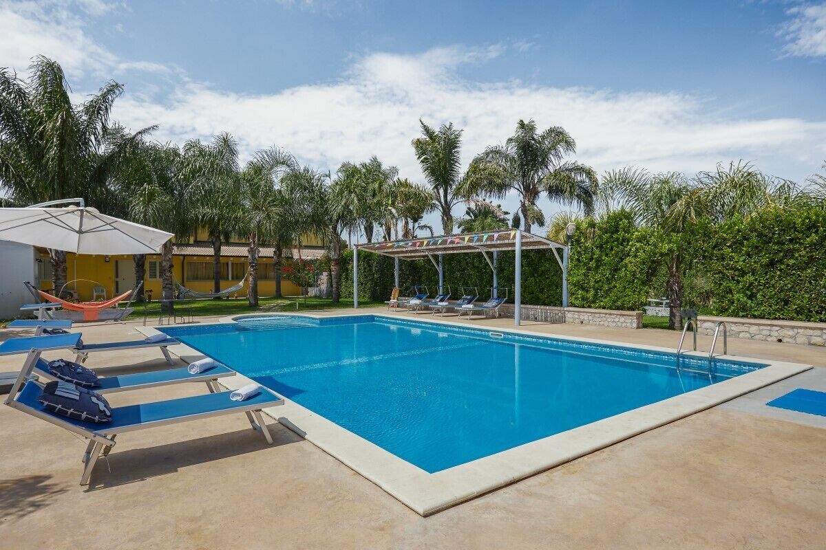 A swimming pool with lounge chairs and a hammock.