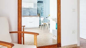 Een kamer met een spiegel met houten lijst, een witte stoel en een betegelde vloer.