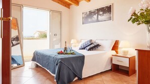 Een slaapkamer met een bed, nachtkastjes, een spiegel, een lijst met foto en een potplant.