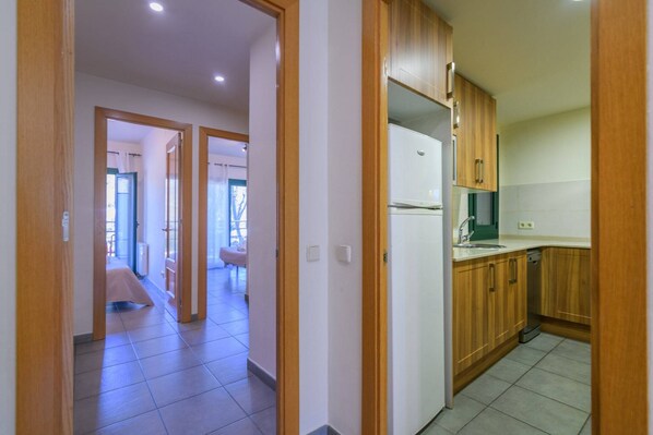 A hallway leading to a kitchen with wooden cabinets and a white refrigerator.
