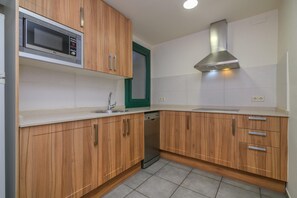 A kitchen with wooden cabinets, a microwave, a dishwasher, and a stainless steel range hood.