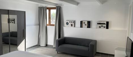 A modern bedroom with a bed, a sofa, a TV, and artwork on the wall.