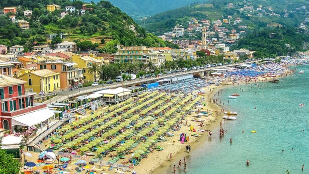 A coastal town with a long beach lined with rows of umbrellas and sun loungers.