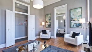 A modern living room with white sofas, a glass coffee table, and artwork on the walls. - An apartment with an amazing terrace (Estoril)
