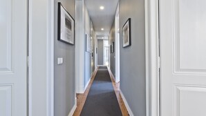 A long, narrow hallway with white walls and a dark carpet. - An apartment with an amazing terrace (Estoril)