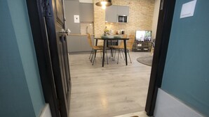 A modern kitchen with a dining area, featuring a brick wall, a microwave, and a dining table with chairs.