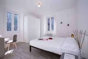 A modern bedroom with a large bed, a desk, and a chair. There are two windows providing natural light. - Menaggio Royale, Menaggio, Italy (Menaggio)