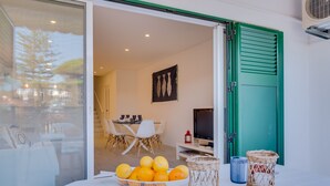 A modern interior with a dining area, a television, and a table with a basket of oranges. - Villa V1 Vale do Lobo Beach - 2 steps to the beach - free wifi - NEW (Vale de Lobo)