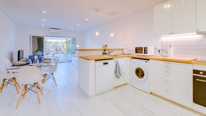 A modern kitchen with white cabinetry, a wooden countertop, and a built-in washing machine. - Villa V1 Vale do Lobo Beach - 2 steps to the beach - free wifi - NEW (Vale de Lobo)