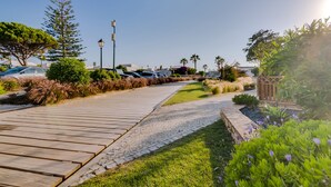A wooden pathway leading to a parking area with cars, surrounded by greenery and palm trees. - Villa V1 Vale do Lobo Beach - 2 steps to the beach - free wifi - NEW (Vale de Lobo)