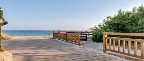 A wooden boardwalk leading to a beach with a clear view of the ocean.
