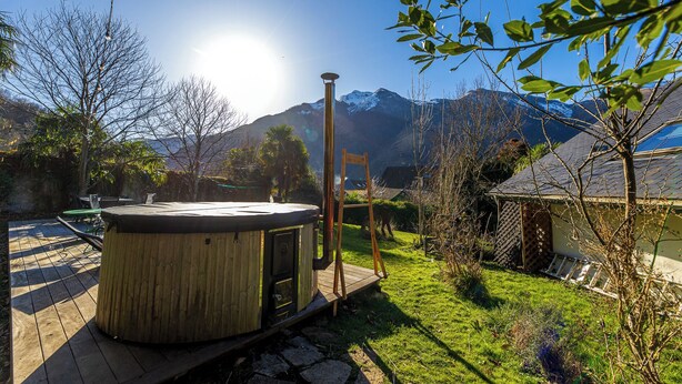 Tinaco de madera en una terraza con montañas al fondo.