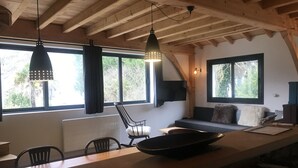 Una cocina moderna con una encimera amplia, vigas de techo de madera y grandes ventanales que ofrecen vistas a la vegetación.