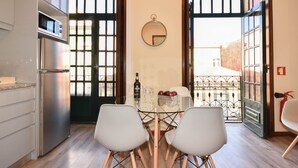 Una cocina compacta con refrigerador, microondas y un comedor con dos sillas y una mesa de vidrio.