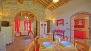A dining area with a long wooden table set for four, stone walls, and a stone fireplace. - Lovely apartment for 4 guests with WIFI, pool, A/C and TV, close to San Gimignano (Poggibonsi)
