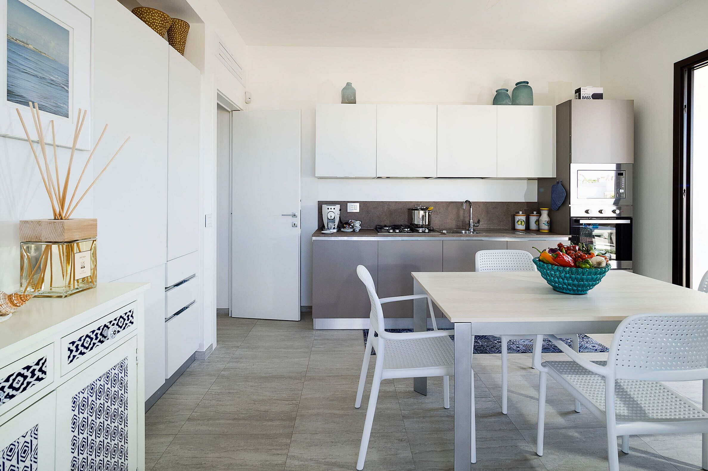 Een moderne keuken met witte kasten, een eethoek met witte stoelen en een keukeneiland.