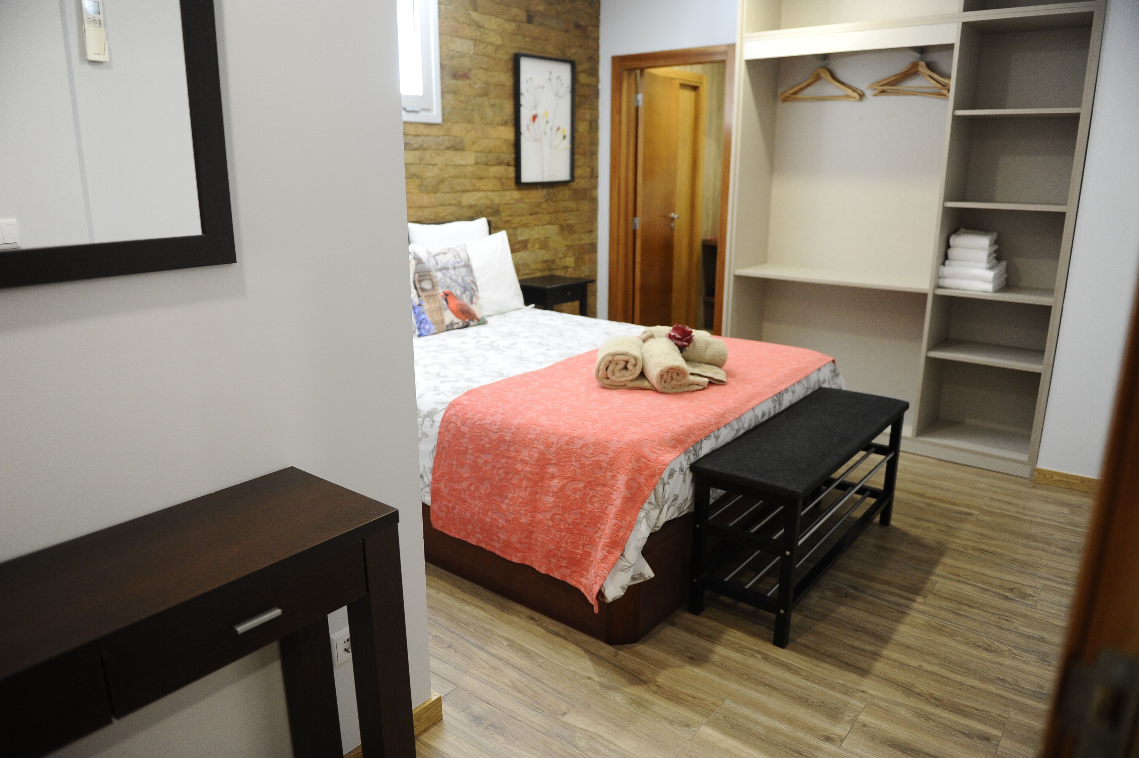Quarto de hotel com cama, um banco, guarda-roupa e espelho.